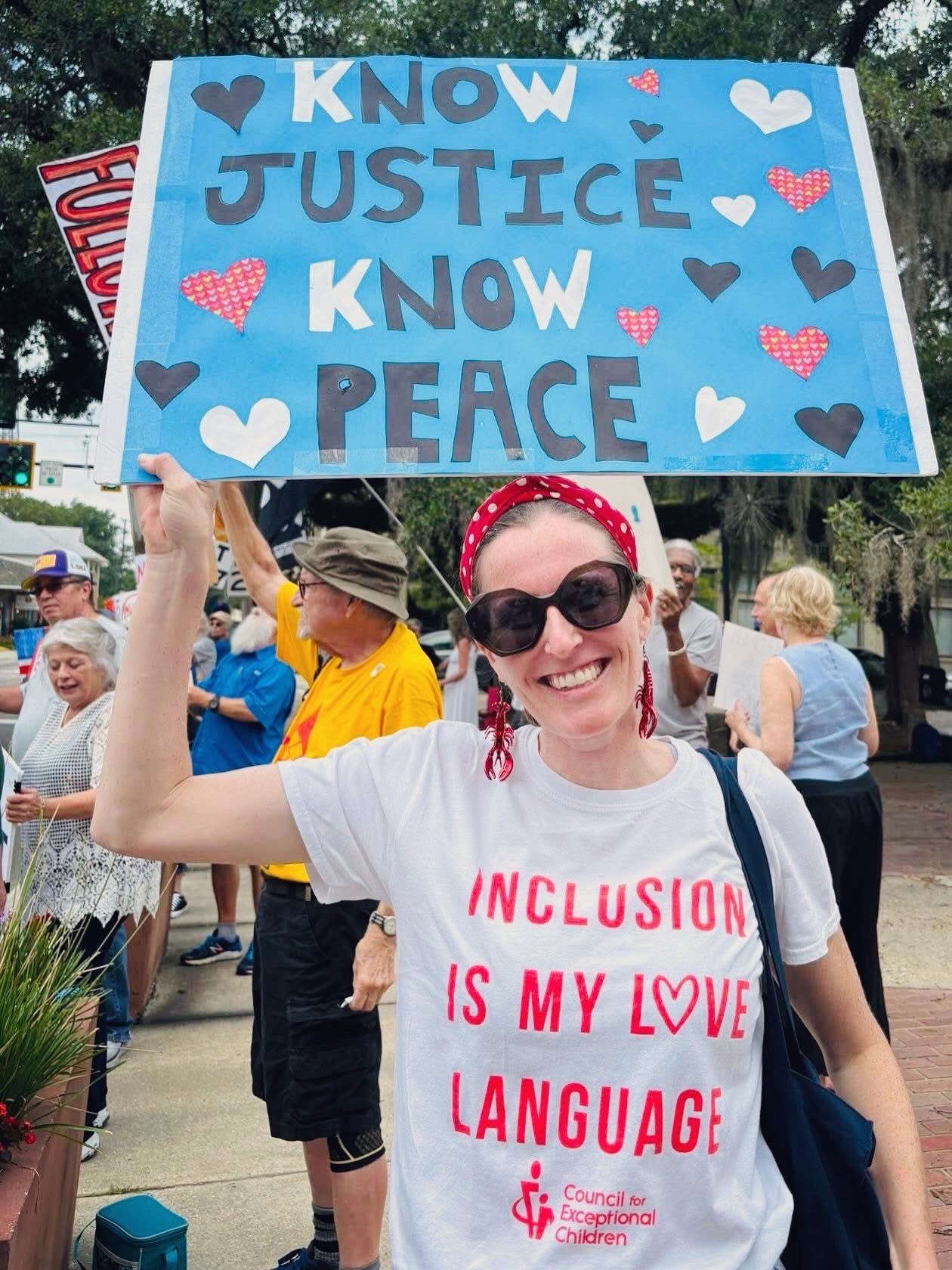 Lauren Jewett holding a sign that reads Know Justice, Know Peace